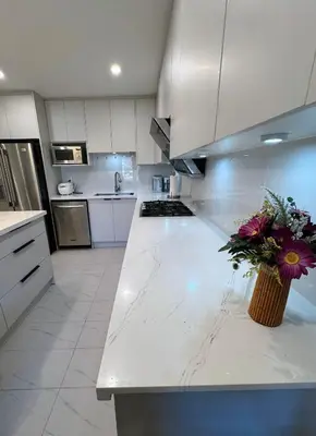 a white kitchen with a vase of flowers on a counter at Modern Newly-Renovated Suite Free Parking in Toronto