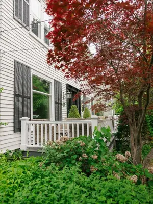 a white house with a white porch and a tree at Guestroom in Old Town | Steps to Lake & Everything in Niagara on the Lake
