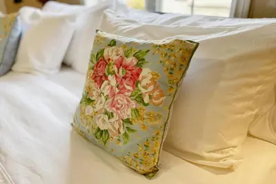 a pillow with a flower pattern on a bed at Top 1% Quiet Private Guestroom 2ppl Old Town NOTL in Niagara on the Lake