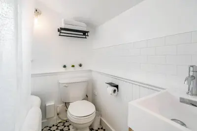 a white bathroom with a toilet and a sink at Top 5% Tiny Home by River/Lake in Old Town NOTL in Niagara on the Lake