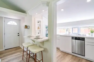 a kitchen with white cabinets and bar stools at Top 5% Tiny Home by River/Lake in Old Town NOTL in Niagara on the Lake