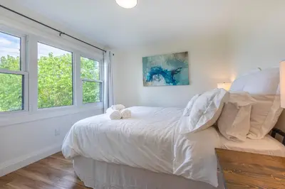 a white bedroom with a bed and two windows at Top 5% Sauna | Bocce Ball | Vineyard Views | NOTL in Niagara on the Lake