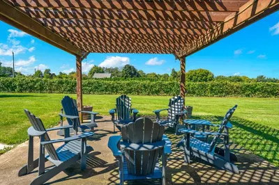 a group of chairs and tables under a pergola at Vineyard Home Pet Friendly NOTL Large Backyard in Niagara on the Lake