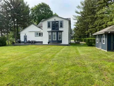 a white house with a large yard with a grass yard at Peaceful 3Bdrm Spacious NOTL Home mins to Town in Niagara on the Lake