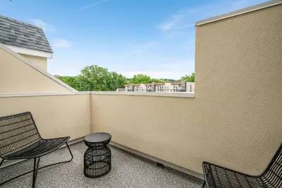 a balcony with two chairs and a stool at 1 Bdrm Luxe Apartment in Niagara in Niagara on the Lake