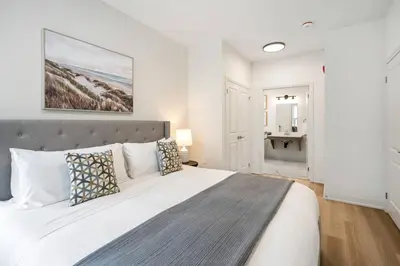 a bedroom with a large white bed and a bathroom at 2 Bdrm Brand New Luxe Niagara Apt - up to 6ppl in Niagara on the Lake