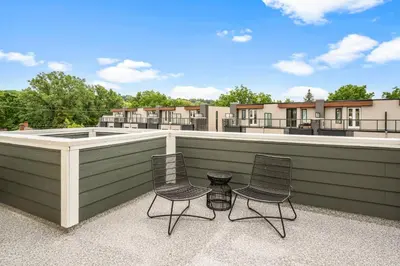 two chairs and a table on a roof with buildings at 2 Brdm Modern Brand New Niagara Apt up to 6 ppl in Niagara on the Lake