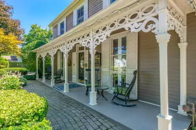 a house with a porch with chairs on a sidewalk at Hot Tub | Historic Home | Steps to Everything NOTL in Niagara on the Lake