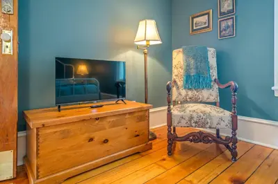 a living room with a chair and a television at Hot Tub | Historic Home | Steps to Everything NOTL in Niagara on the Lake