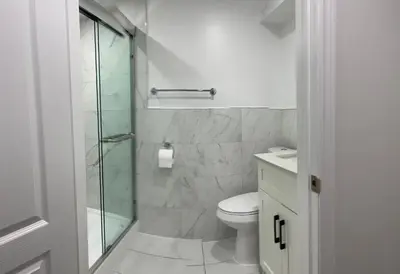 a bathroom with a toilet and a glass shower at Rayann Hospitality in Toronto