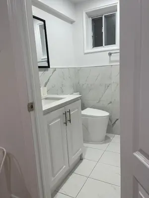 a white bathroom with a sink and a toilet at Hanan Hospitality in Toronto