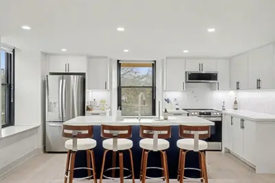 a kitchen with white cabinets and a island with bar stools at The Wynford Dreamy Capri Suite in Elora