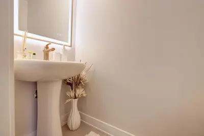 a white bathroom with a sink and a mirror at Charming Mississauga Getaway in Mississauga