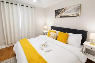 a bedroom with a large white bed with yellow accents at 4-Bed, 3 bath Luxury Home in Oakville - Prime location in Oakville
