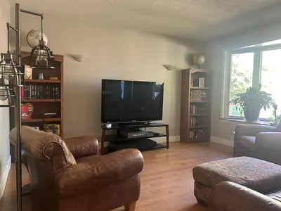 a living room with a television and a couch and chairs at Cozy Home Away From Home in Kitchener