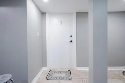 a white room with a door and a rug on the floor at Renovated 2 Bedroom Basement Apartment Near 401 and Amenities in Bowmanville