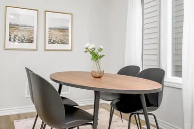 a dining room table with chairs and a vase with flowers at Stylish and Cozy Muskoka Vacation Home in Gravenhurst