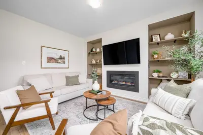 a living room with white furniture and a fireplace at Stylish and Cozy Muskoka Vacation Home in Gravenhurst