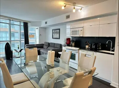 a kitchen and a living room with a glass table and chairs at Spacious two-bedroom abode in the heart of TO in Toronto