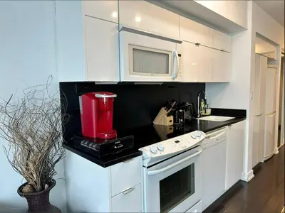 a kitchen with white cabinets and a red appliance at Spacious two-bedroom abode in the heart of TO in Toronto
