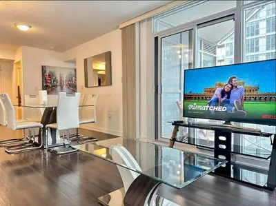 a living room with a large tv and a table and chairs at Spacious two-bedroom abode in the heart of TO in Toronto