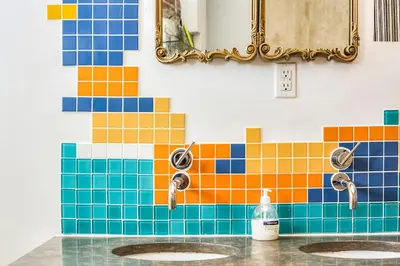 a bathroom with two sinks and a colorful tile wall at Unique Above Garage Loft in Toronto