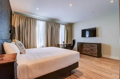 a hotel room with a bed and a flat screen tv at Dream Suites Near YYZ Airport in Mississauga