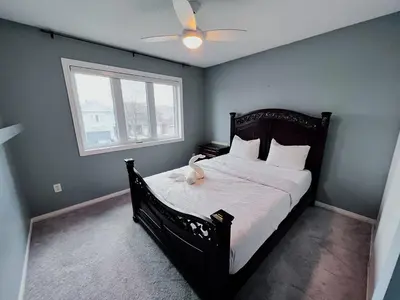a bedroom with a black bed with a ceiling fan at Family Comfort Retreat in Brampton