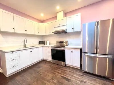 a kitchen with white cabinets and a stainless steel refrigerator at Quiet King Bedroom near DT Toronto in Toronto