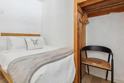 a small bedroom with a bed and a chair at 8 Bedroom Blue Mountain Chalet with Ping-Pong - 218 Arlberg in Blue Mountains