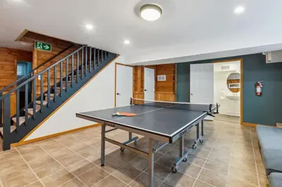 a ping pong table in a living room with a staircase at 8 Bedroom Blue Mountain Chalet with Ping-Pong - 218 Arlberg in Blue Mountains