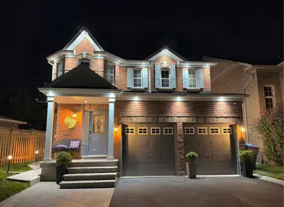 a house with two garage doors at night at Modern Cozy Basement Suite Free Parking in Brampton
