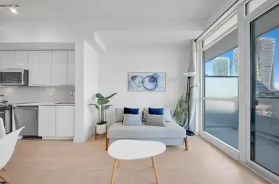 a white living room with a couch and a kitchen at Tranquil Lakeside Suite Toronto in Toronto
