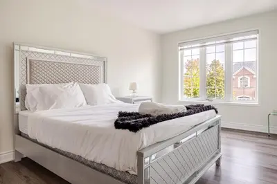 a white bedroom with a large bed with a large window at Comfortable Brampton Getaway 3BR, 3BA, 4 Beds in Brampton