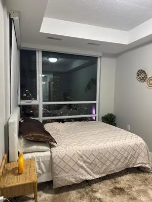 a bedroom with a bed and a large window at One-Bedroom Apartment with Den With Amazing Views of Hamilton in Hamilton