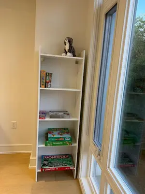 a book shelf with a stuffed animal on it next to a window at Brand New Chic Townhouse in Toronto close to Yonge in Toronto
