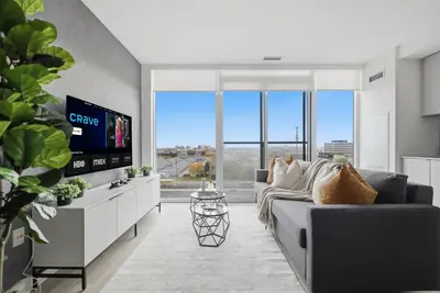 a living room with a couch and a flat screen tv at Stylish 2BR Retreat Parking & Sleeps 6 in Toronto