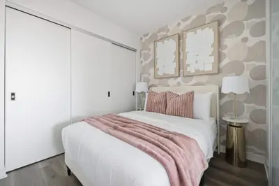 a bedroom with a white bed with a pink blanket at Elegant 2BR Condo with 55 TV & City Views in Toronto