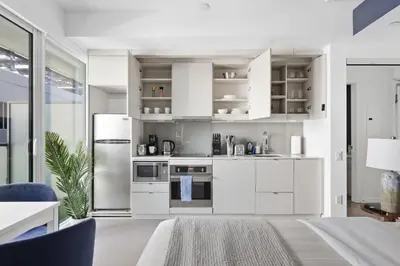 a kitchen with white cabinets and a refrigerator at Chic Downtown TO Studio Near Entertainment Dist in Toronto