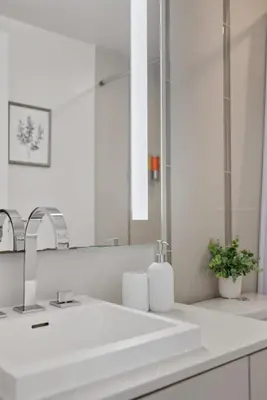 a white bathroom with a sink and a mirror at Chic Downtown TO Studio Near Entertainment Dist in Toronto