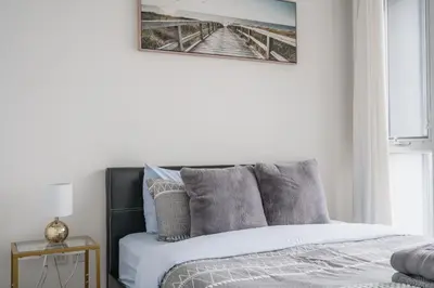 a bedroom with a bed with a picture on the wall at Stylish Modern Condo in the Heart of Toronto in Toronto