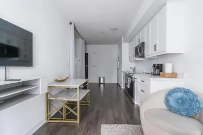 a white kitchen with a couch and a table at Stylish Modern Condo in the Heart of Toronto in Toronto