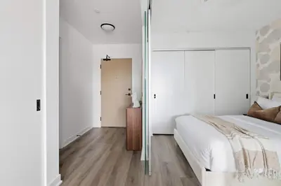a bedroom with white walls and a bed and a wooden floor at Modern West Getaway 2BR Condo with Free Parking in Toronto