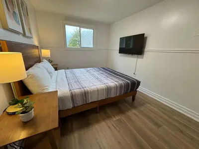 a bedroom with a bed and a tv on the wall at North Barrie !D Stylish and Cozy Private Bedroom with Shared Bathroom in Barrie
