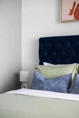 a bed with a blue headboard and some pillows at Modern 4BR Home Sleeps 12 Steps to CN Tower in Toronto