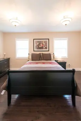 a large black bed in a room with two windows at WALK TO THE BEACH in Fort Erie