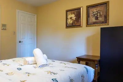 a bedroom with a bed and a table and two pictures at Elegant Mansion with Private Bar & Game Lounge in Mississauga