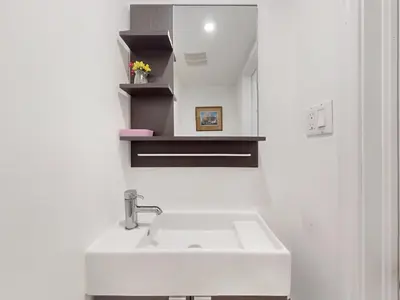 a white bathroom with a sink and a mirror at Cozy Queen room with Shared Bath near Seneca Finch 404 in Toronto