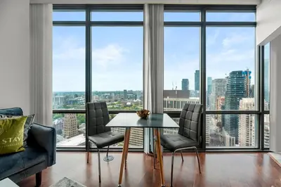 a living room with a table and chairs and large windows at 1 Bedroom Condo Burano Downtown Toronto in Toronto