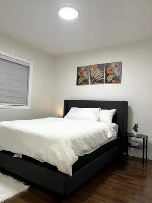 a bedroom with a large bed with white sheets at Cozy 2-Bed with Kitchen and Patio in Midtown Toronto in Toronto